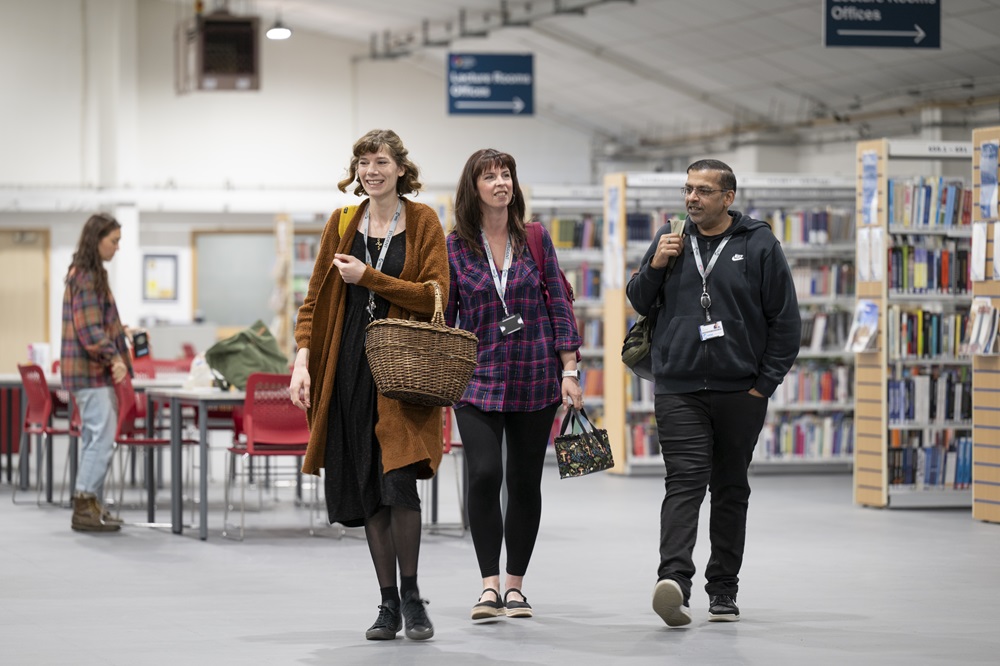 Students walking along indoors with a library in the background