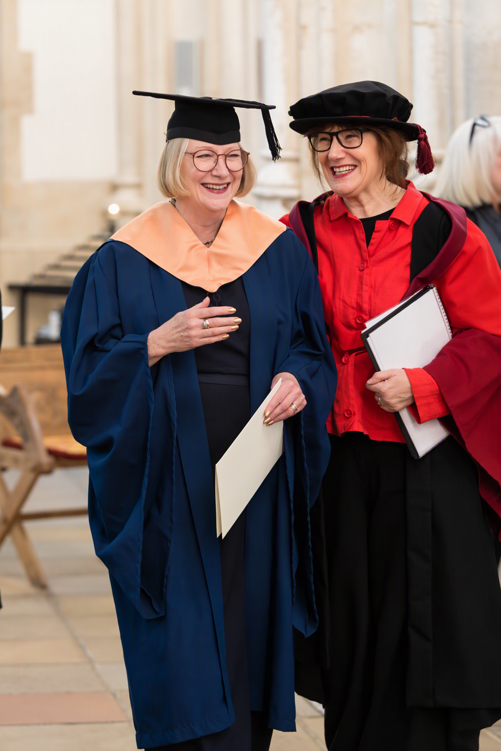 Two elderly ladies chatting at a graduation ceremony.