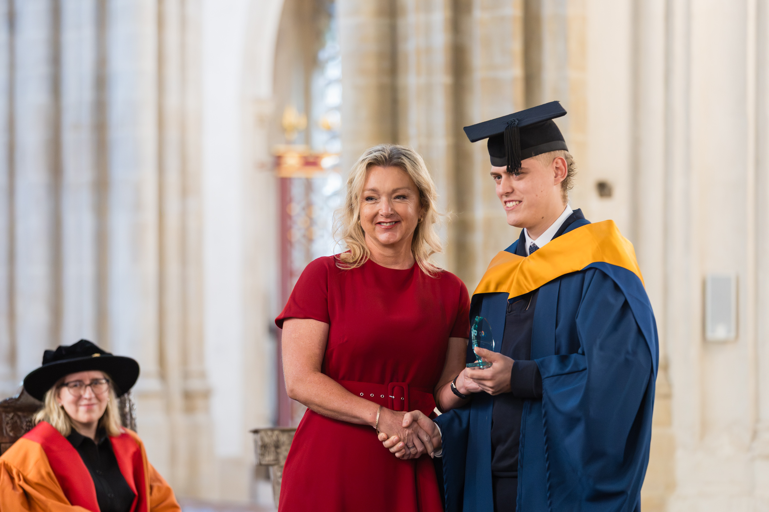 A smiling lady in a red dress with a graduate